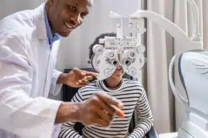 optometrist doing eye test of a girl using phoropter in clinic
