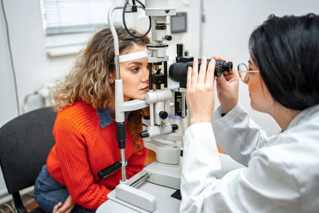 Optometrist performing eye exam with optical equipment on female patient