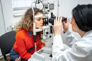 Optometrist performing eye exam with optical equipment on female patient