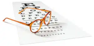 Orange eyeglasses sitting on visual test chart used for vision loss.