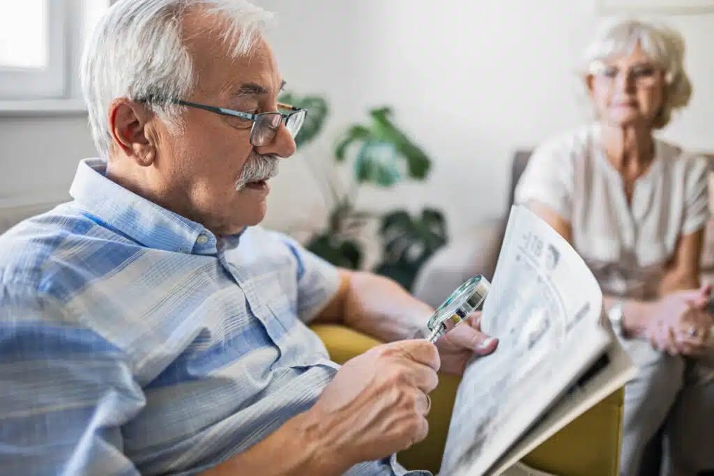 senior man with Macular Degeneration olding an magnifying glass he uses to help him read