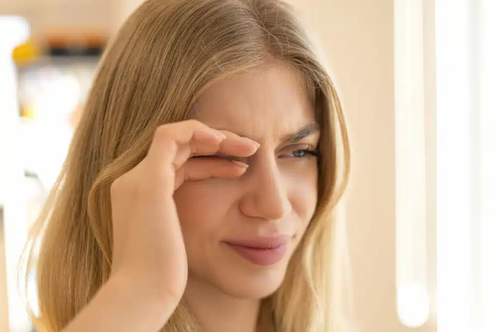 A woman is rubbing her eyes because she is experiencing dry eye syndrome.